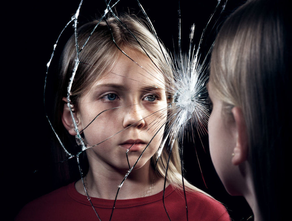 Kind vor zerbrochenem Spiegel